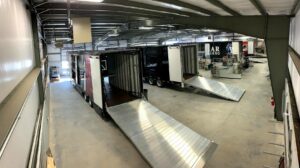 Photo from inside the clubhouse of four partly-completed trailers with full lift ramps