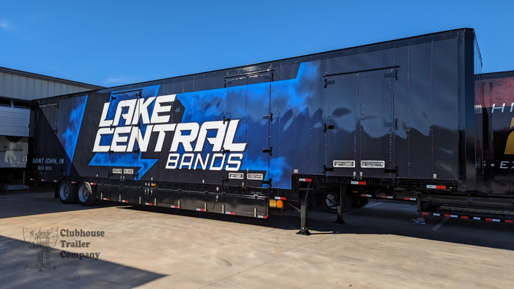 Blue and black custom vinyl wrap on a high school marching band semi trailer build out.