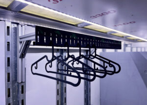 Slotted uniform racks for marching band uniforms with labeled numbers and graphic logo