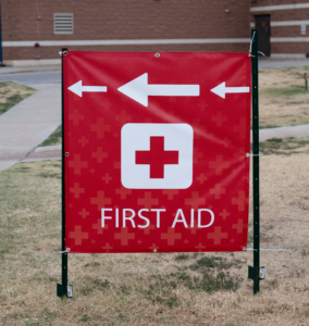 Custom digitally printed first aid banner for high school marching band contest with hemmed edge and grommets.